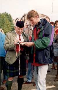 A Scottish veteran is signing a Dutch flag with his name and unit